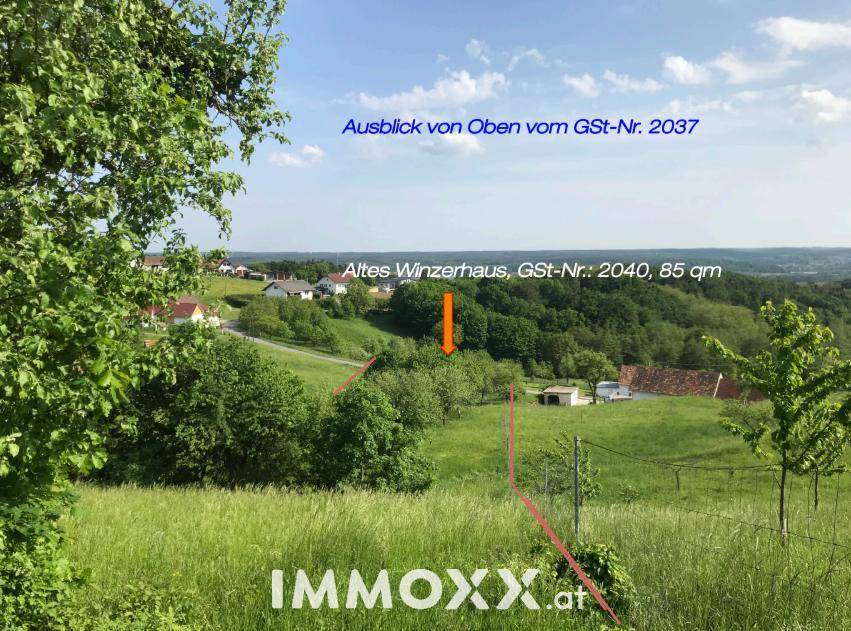 Panoramablick über eine grüne Landschaft mit einem alten Winzerhaus und weiteren Gebäuden in der Ferne.