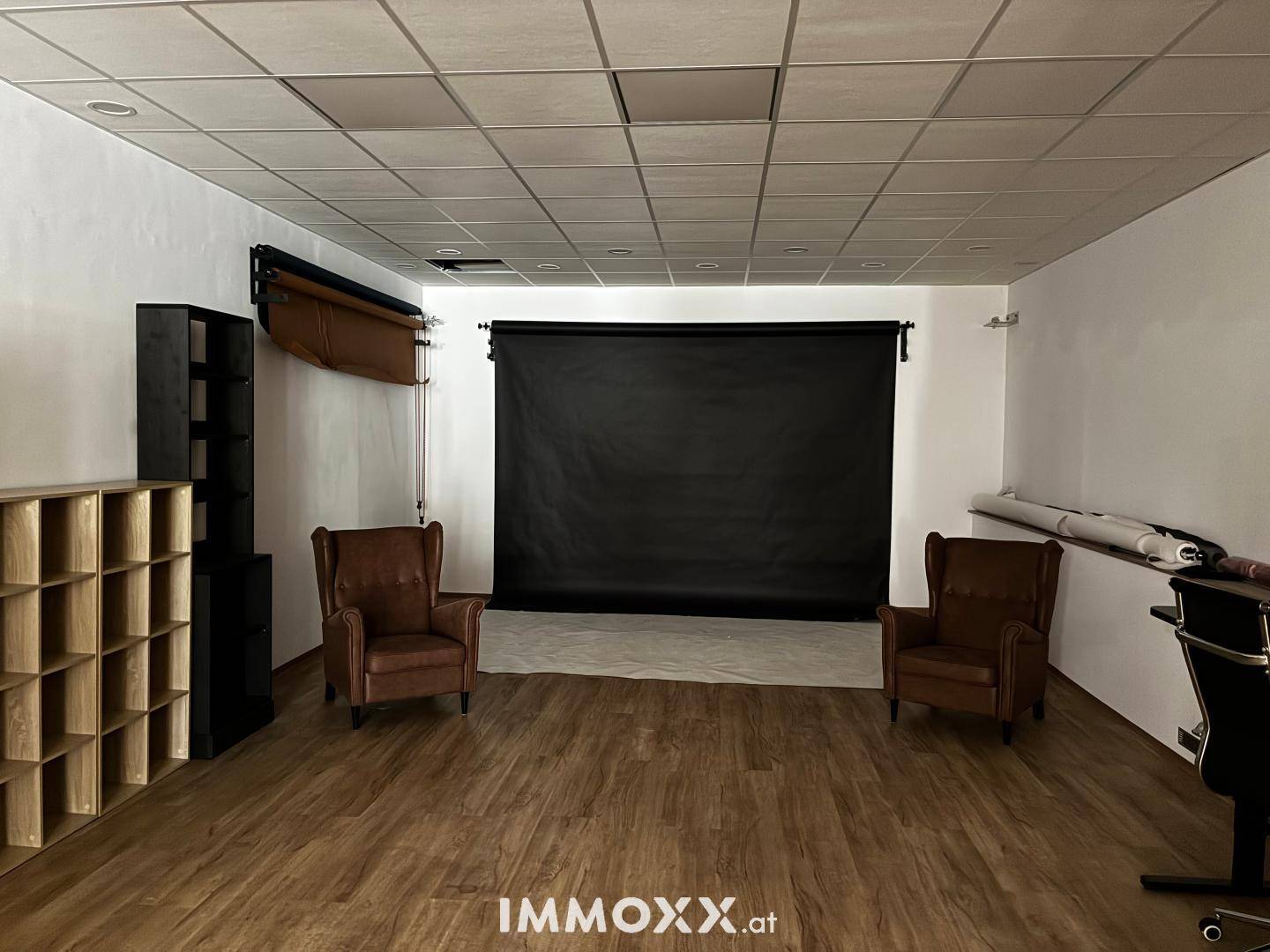 Vielseitiger Raum mit Holzfußboden und schwarzem Hintergrund, nutzbar als Fotostudio oder flexible Arbeitsfläche.