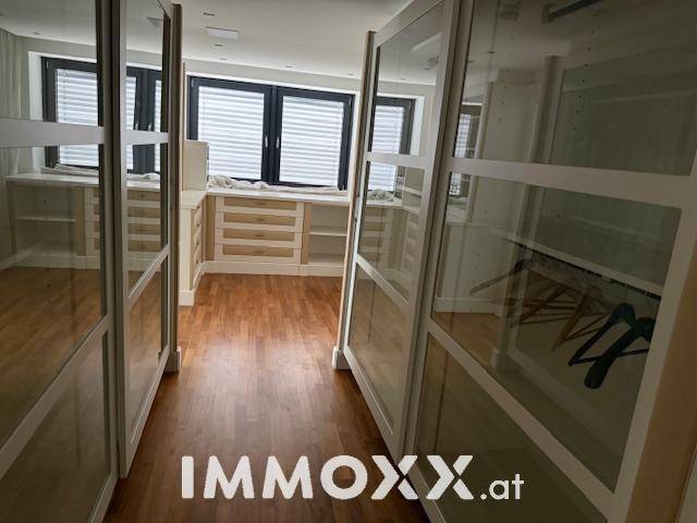 Begehbarer Kleiderschrank mit Holzschubladen, Regalen und Fenstern für Tageslicht.