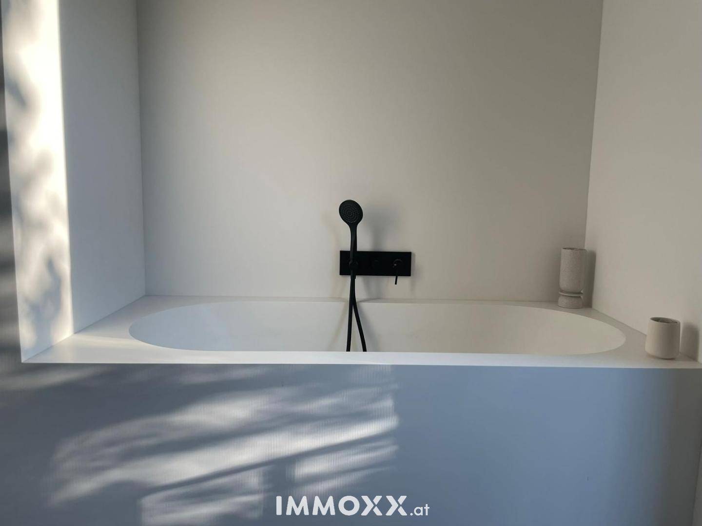 Elegante, minimalistische Badewanne mit schwarzer Armatur, eingebettet in eine moderne weiße Struktur.