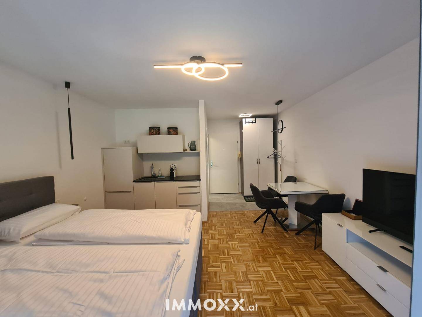 Modernes Studio-Apartment mit integrierter Küchenzeile, Schlafbereich und Essplatz.