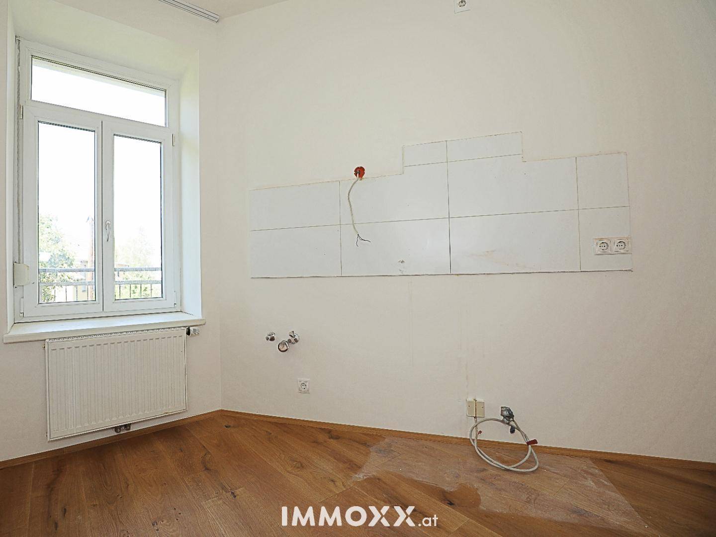 Leerer Küchenbereich mit vorbereiteten Anschlüssen und Fliesen an der Wand, mit Fenster.