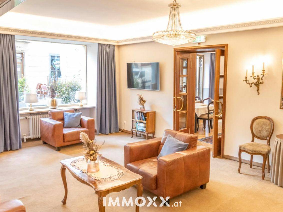 Gemütlicher Hotelloungebereich mit bequemen Ledersesseln, einem Couchtisch und einem eleganten Kronleuchter.