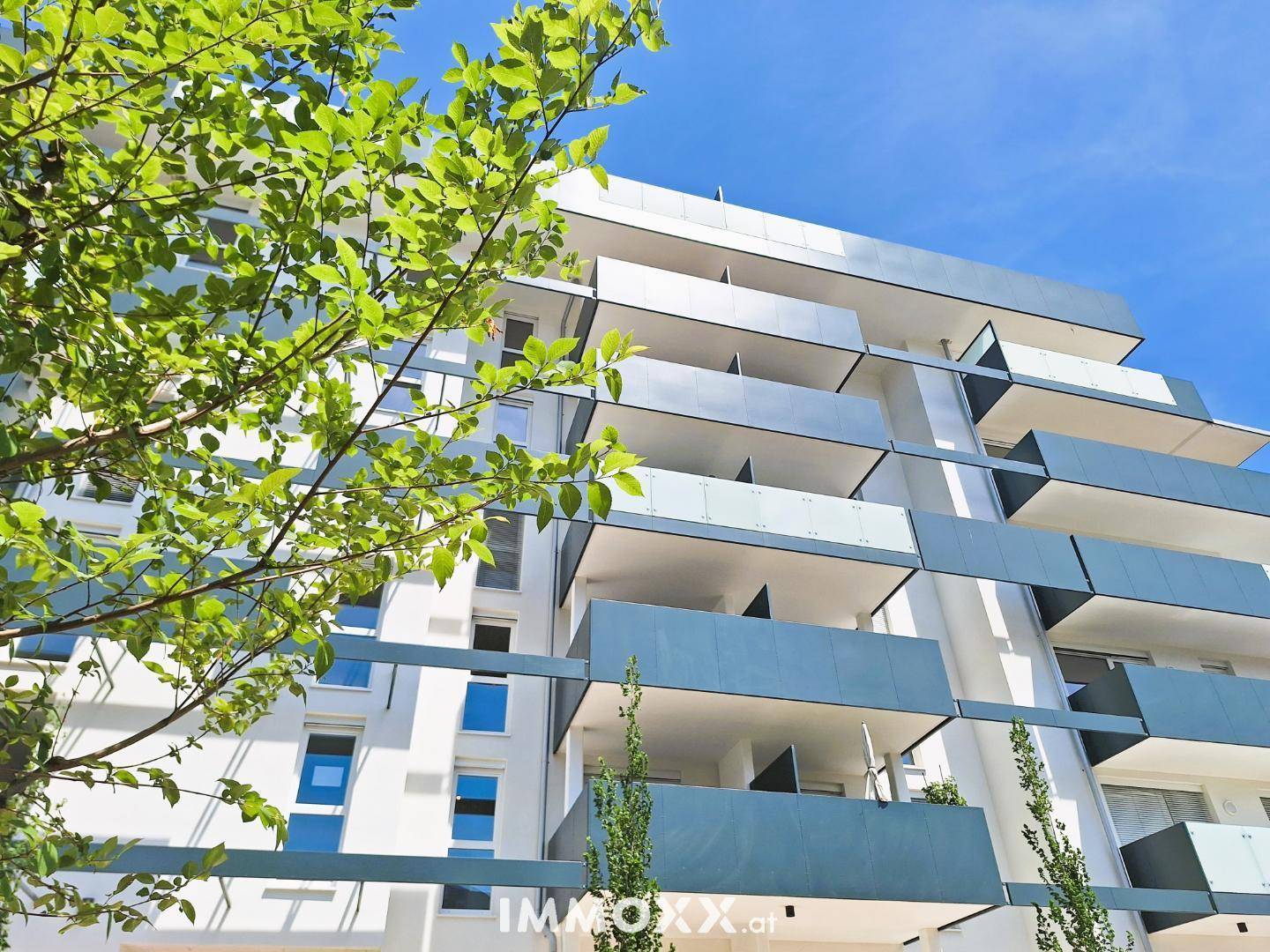 Zeitgenössische Architektur mit gestuften Balkonen und großen Fenstern unter klarem Himmel.