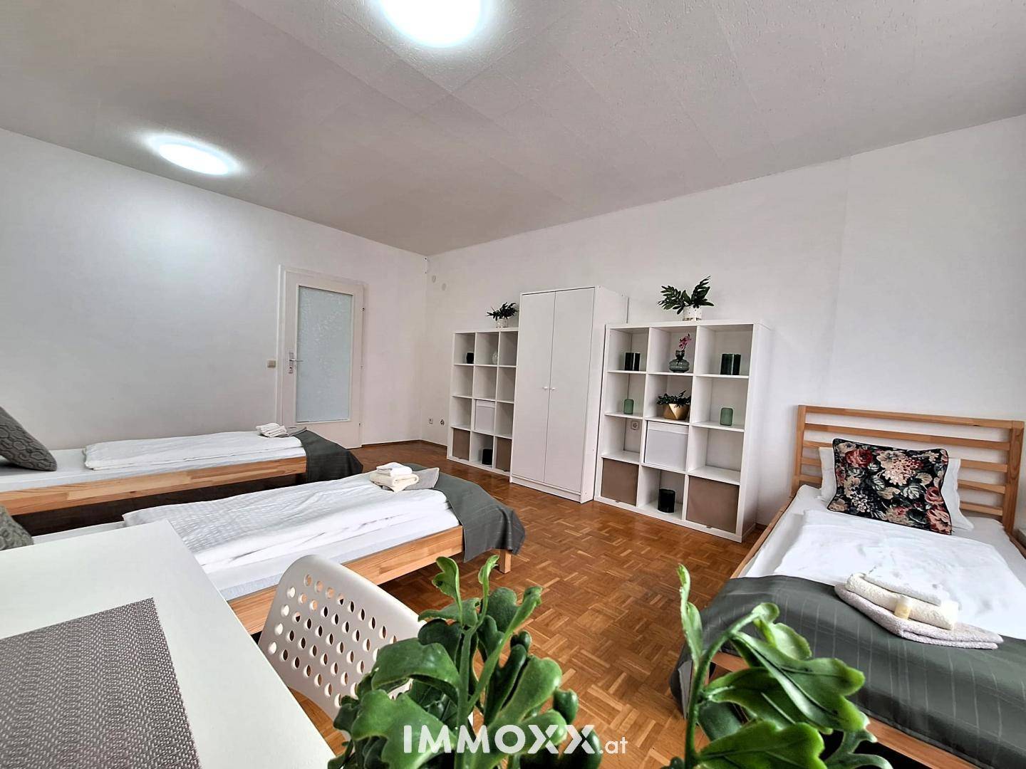 Geräumiges Schlafzimmer mit drei Einzelbetten, Parkettboden und Stauraum.