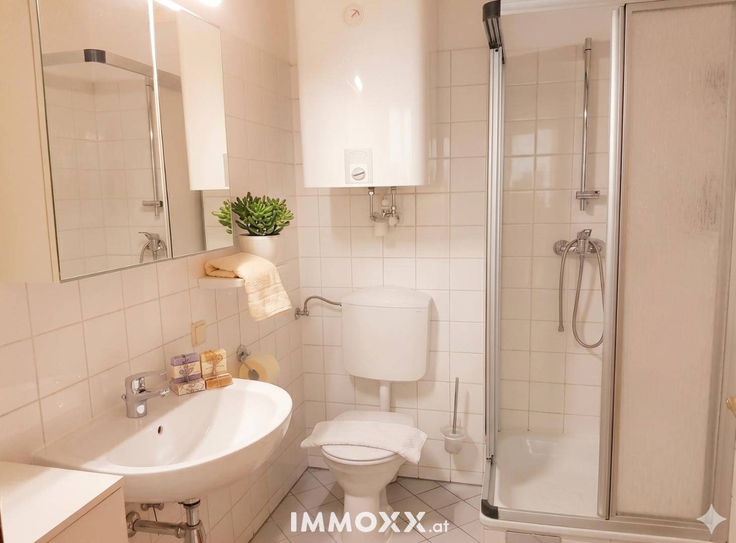 Funktionales Badezimmer mit Dusche, WC und Waschbecken in hellen Fliesen.