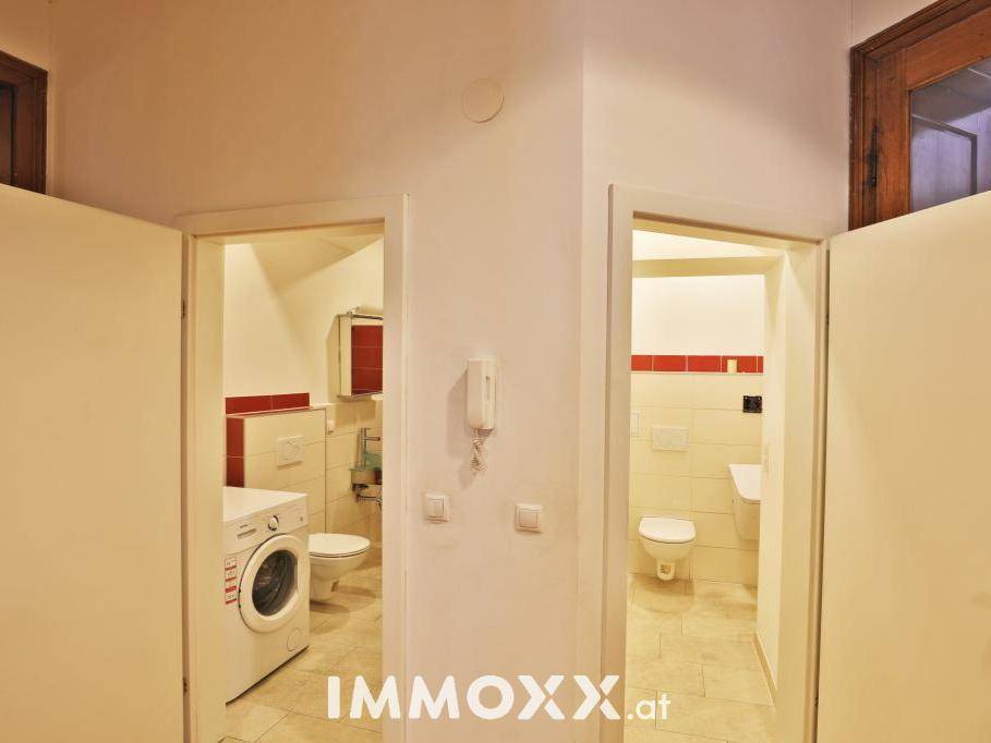 Zwei separate Toilettenräume, einer mit Waschmaschine, beide mit Fliesenboden und modernen Armaturen.