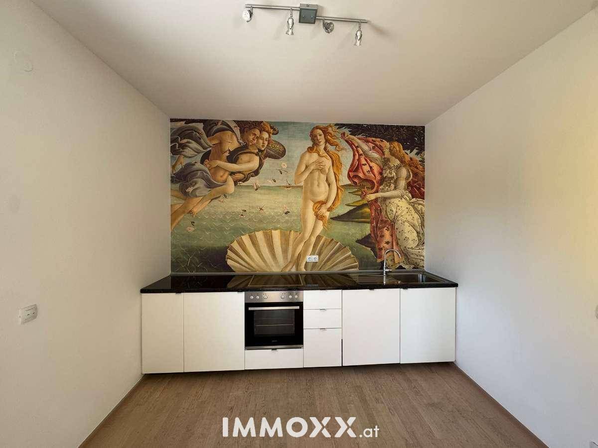 Moderne Küche mit weißen Schränken, Backofen und auffälligem Wandbild als Spritzschutz.