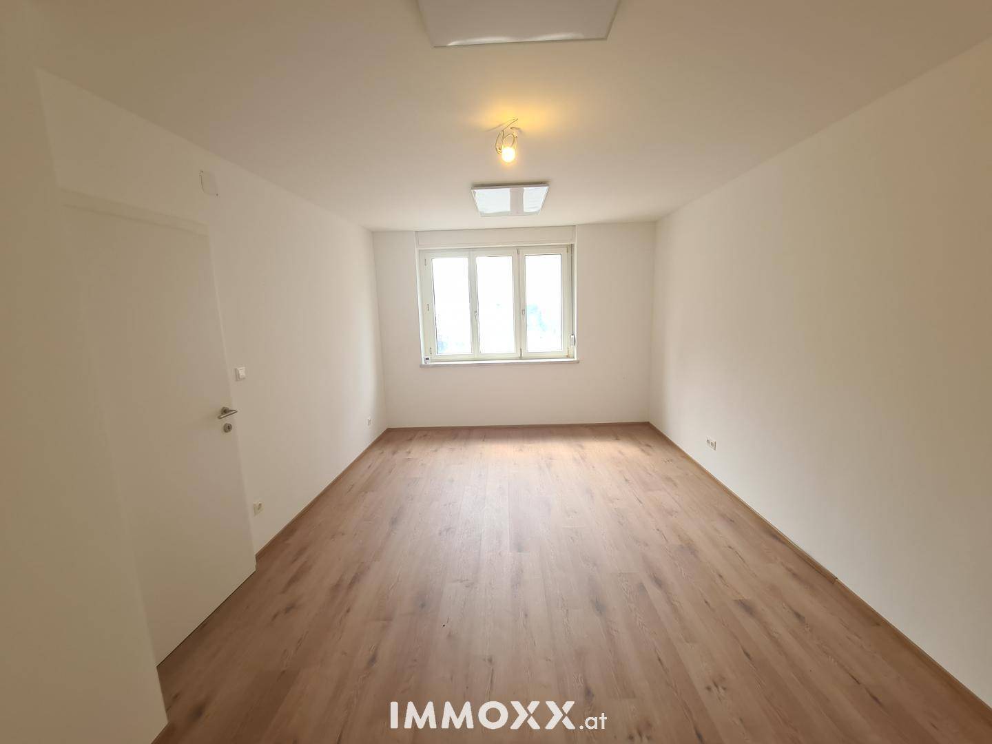 Heller, leerer Raum mit Laminatboden und weiß gestrichenen Wänden, ideal für neue Bewohner.