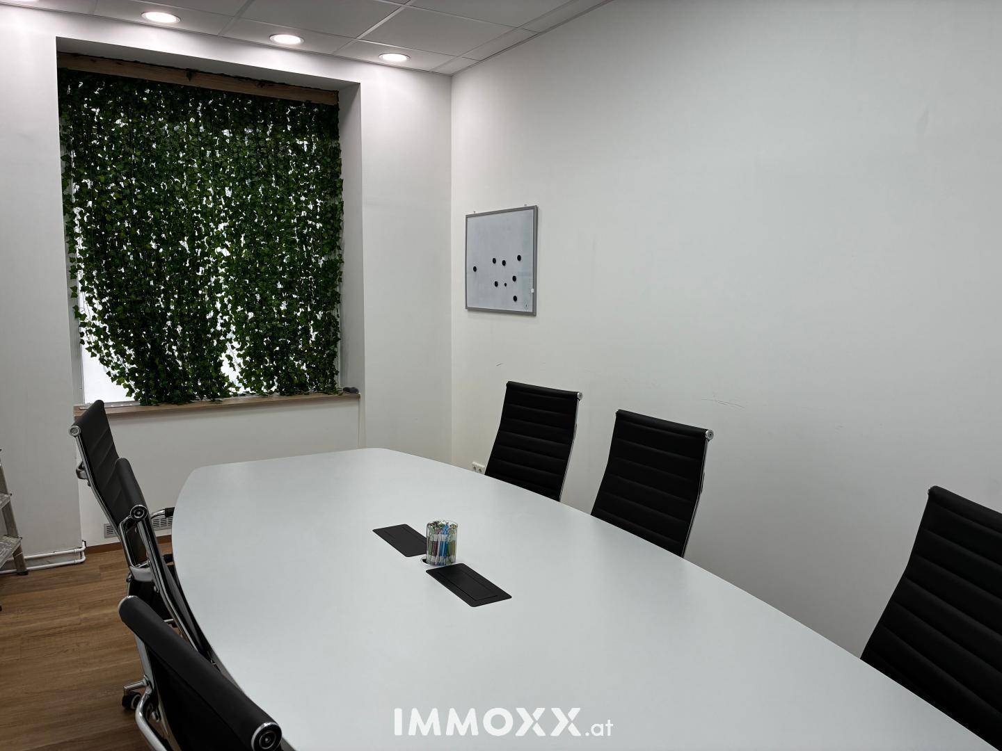 Moderner Konferenzraum mit großem ovalen Tisch und grüner Wanddekoration, perfekt für produktive Meetings.