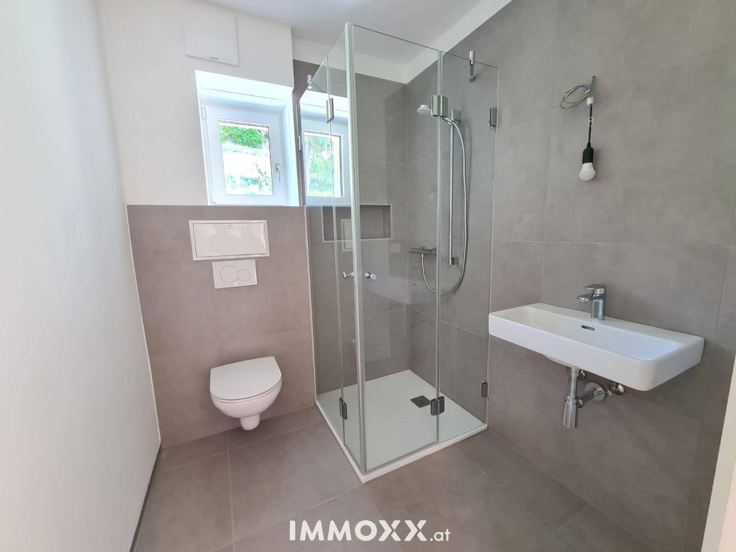Modernes Badezimmer mit ebenerdiger Dusche, Hänge-WC und Fenster für frische Luft.