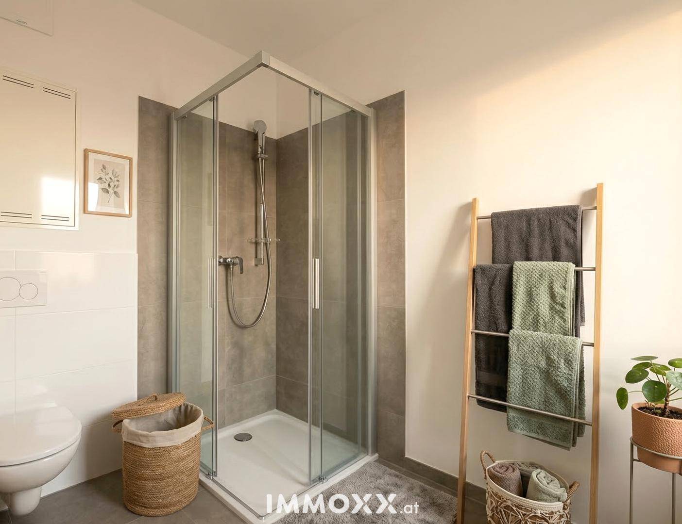 Modernes Badezimmer mit Duschkabine, Wand-WC und grauen Fliesen.