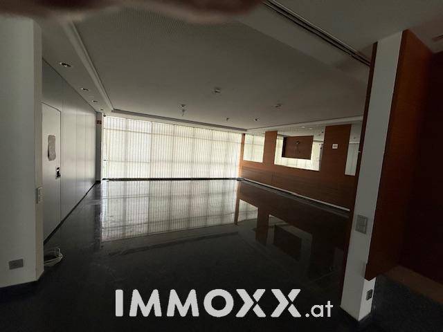 Großes, offenes Büro mit dunklem Steinboden, Fensterfront und Holzakzenten an der Wand.