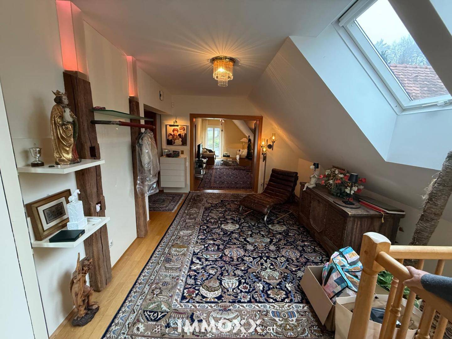 Heller Dachgeschossflur mit schrägen Decken, Dachfenster, langem Teppich und dekorativen Elementen.