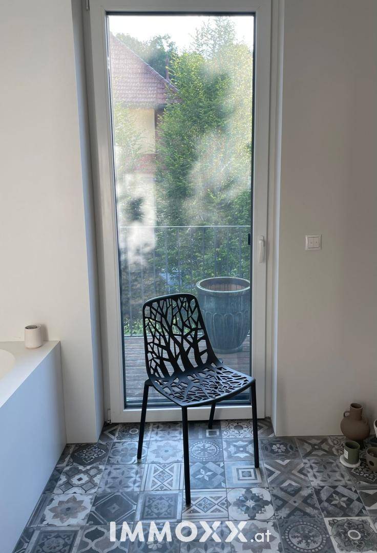 Modernes Badezimmer mit gemusterten Fliesen, Badewanne und großem Fenster für viel Tageslicht.