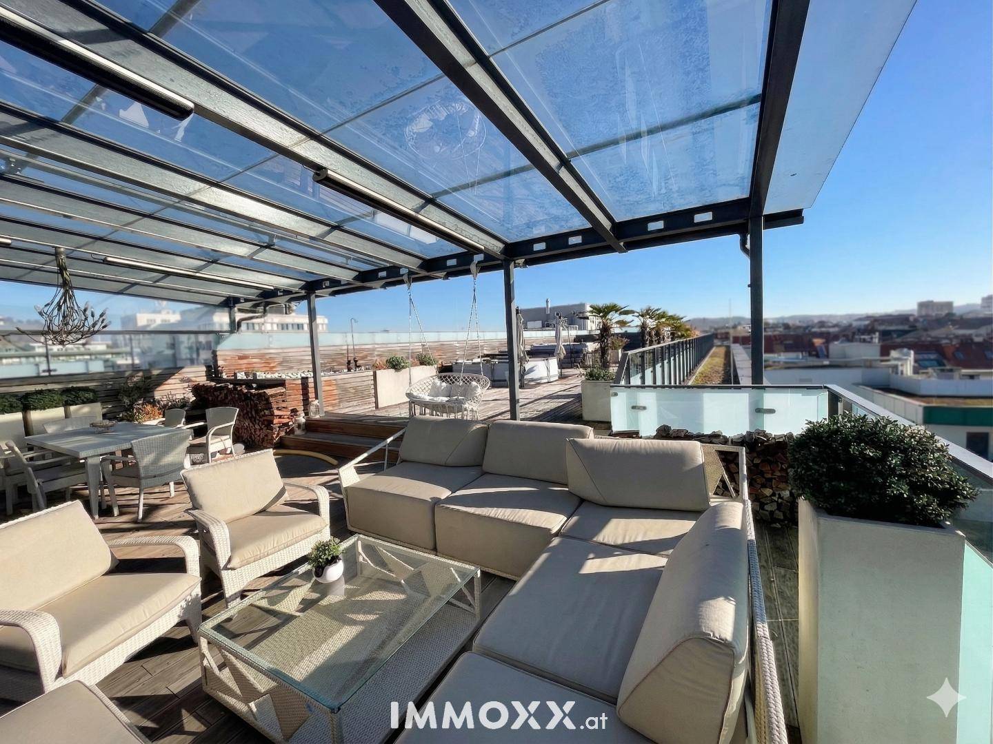 Geräumige Dachterrasse mit bequemen Lounge-Möbeln und weitem Stadtblick unter Glasdach.