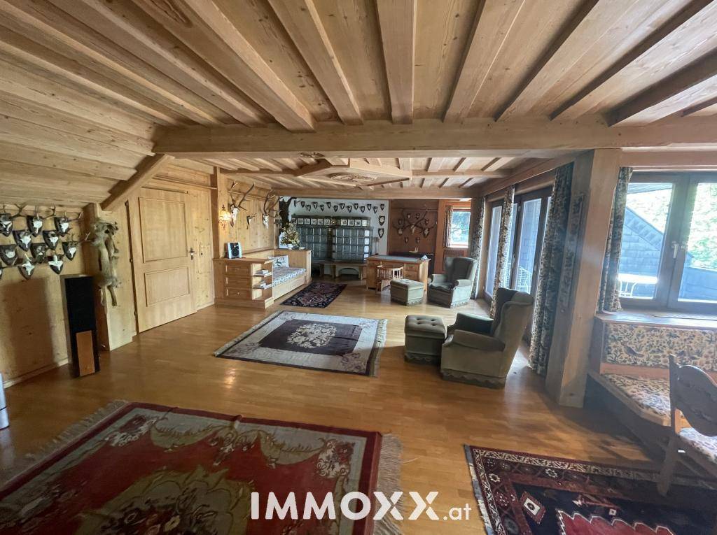 Traditionelles Wohnzimmer im alpinen Stil mit Holzbalkendecke und rustikalen Möbeln.