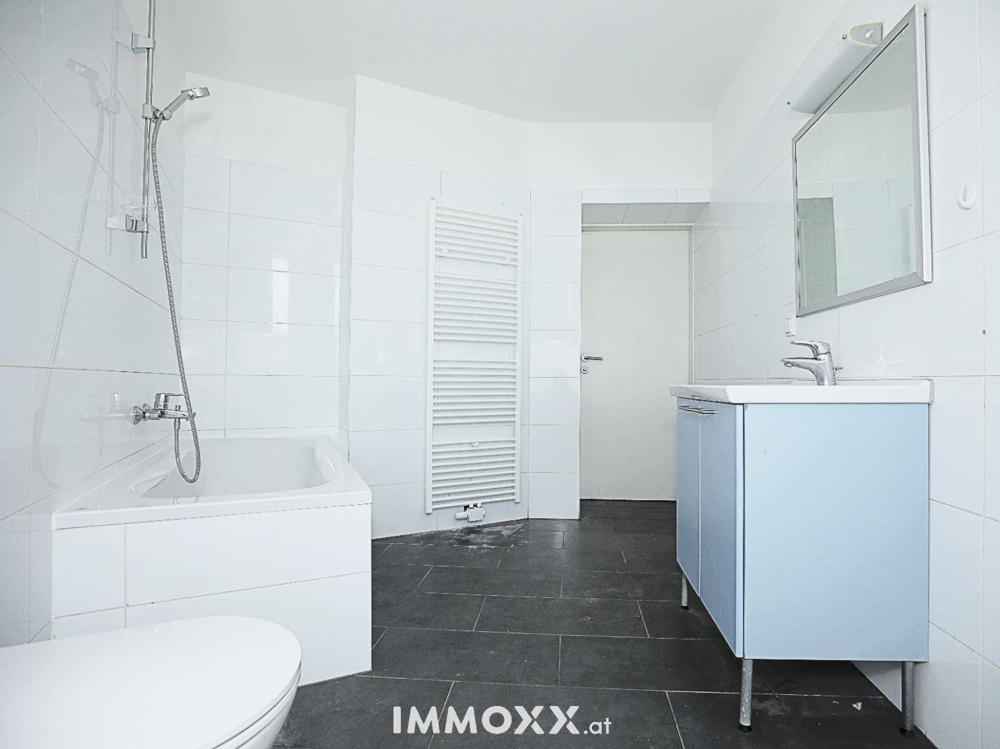 Badezimmer mit Badewanne, Waschbecken, Toilette und beheiztem Handtuchhalter, funktional und hell.