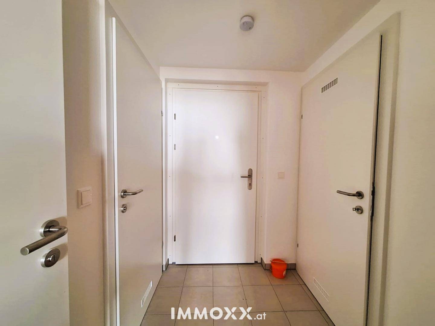 Eingangsbereich einer Wohnung mit weiß gestrichenen Wänden und Fliesenboden.