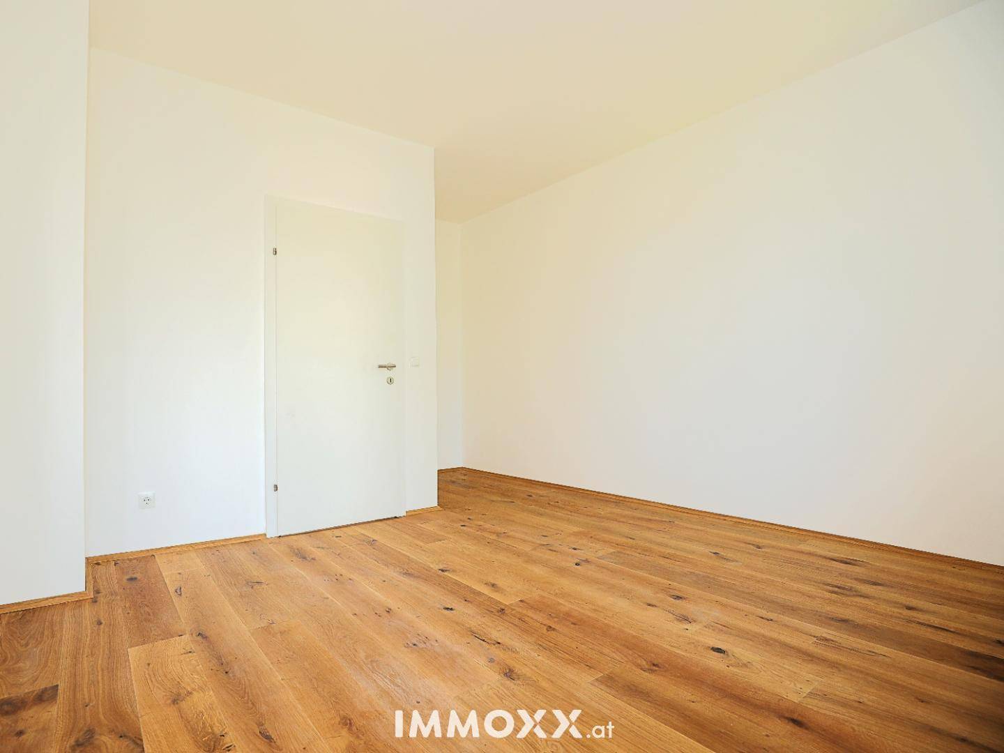 Leerer Raum mit Holzboden und einer weißen Tür, bereit für die individuelle Gestaltung.