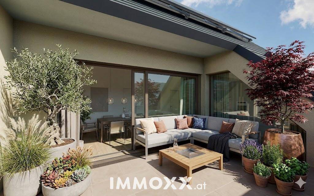Geräumige Terrasse mit bequemen Lounge-Möbeln und dekorativen Pflanzen, ideal zum Entspannen im Freien.