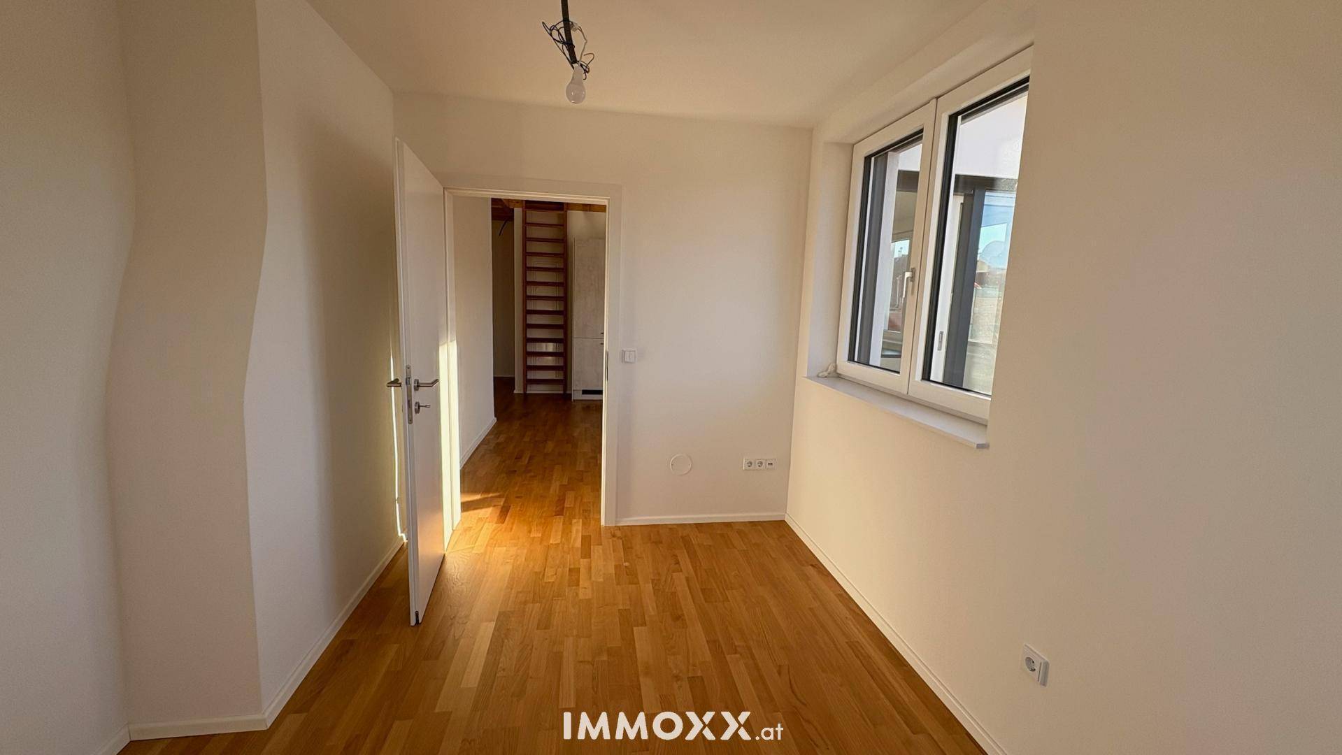 Helles Zimmer mit Holzboden und großem Fenster, bereit zur individuellen Gestaltung.