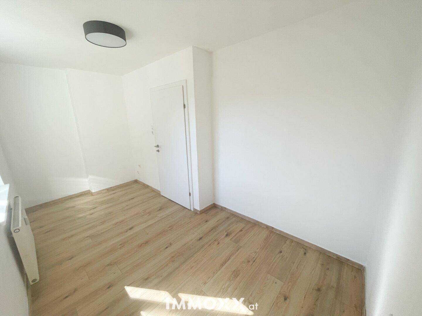 Leerer Raum mit Holzboden und weiß gestrichenen Wänden, bereit zur individuellen Gestaltung.