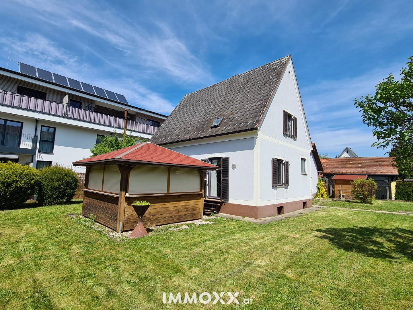 Rückansicht des Hauses mit Garten, Rasenfläche und einem hölzernen Gartenpavillon.