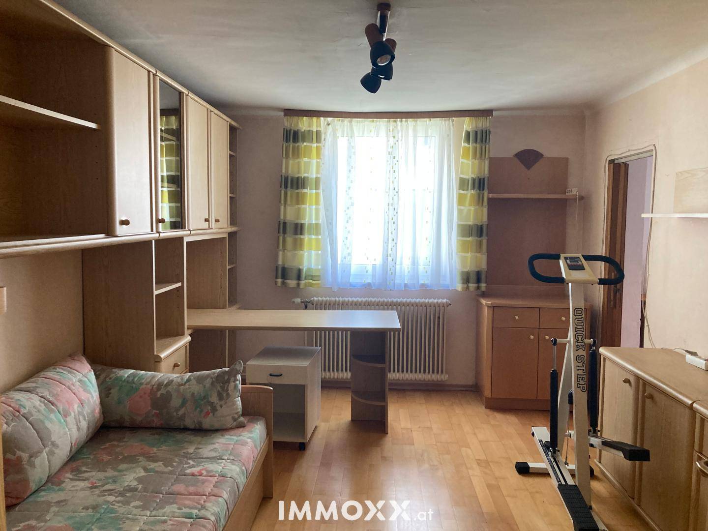 Helles Schlafzimmer mit Holzparkett, Schreibtisch und praktischen Einbauschränken.