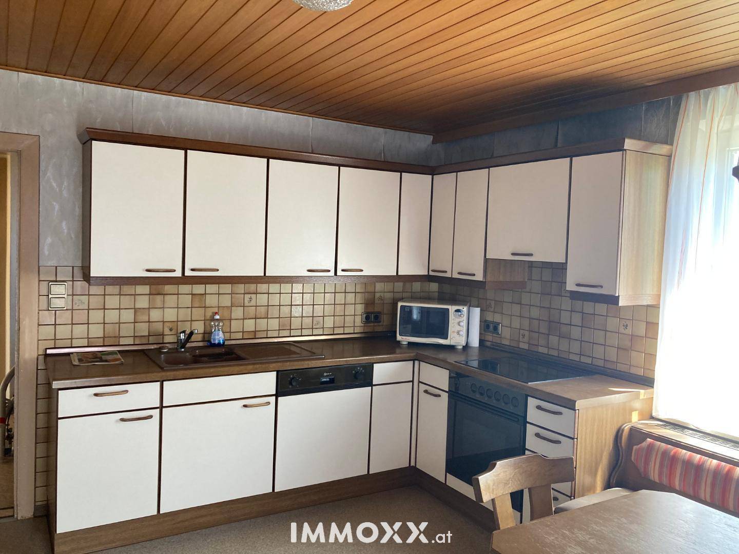 Funktionale Einbauküche mit Holzdecke, integrierten Geräten und Essbereich.