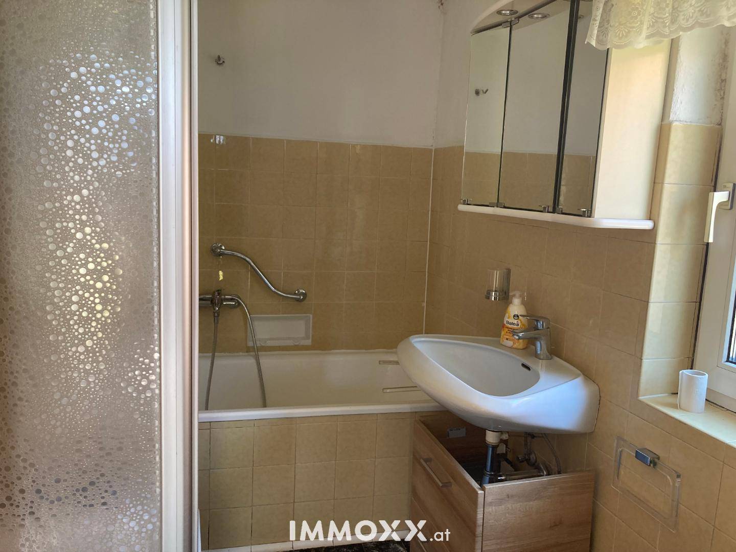 Badezimmer mit gelben Fliesen, Badewanne und Waschbecken, ausgestattet mit Spiegelschrank.