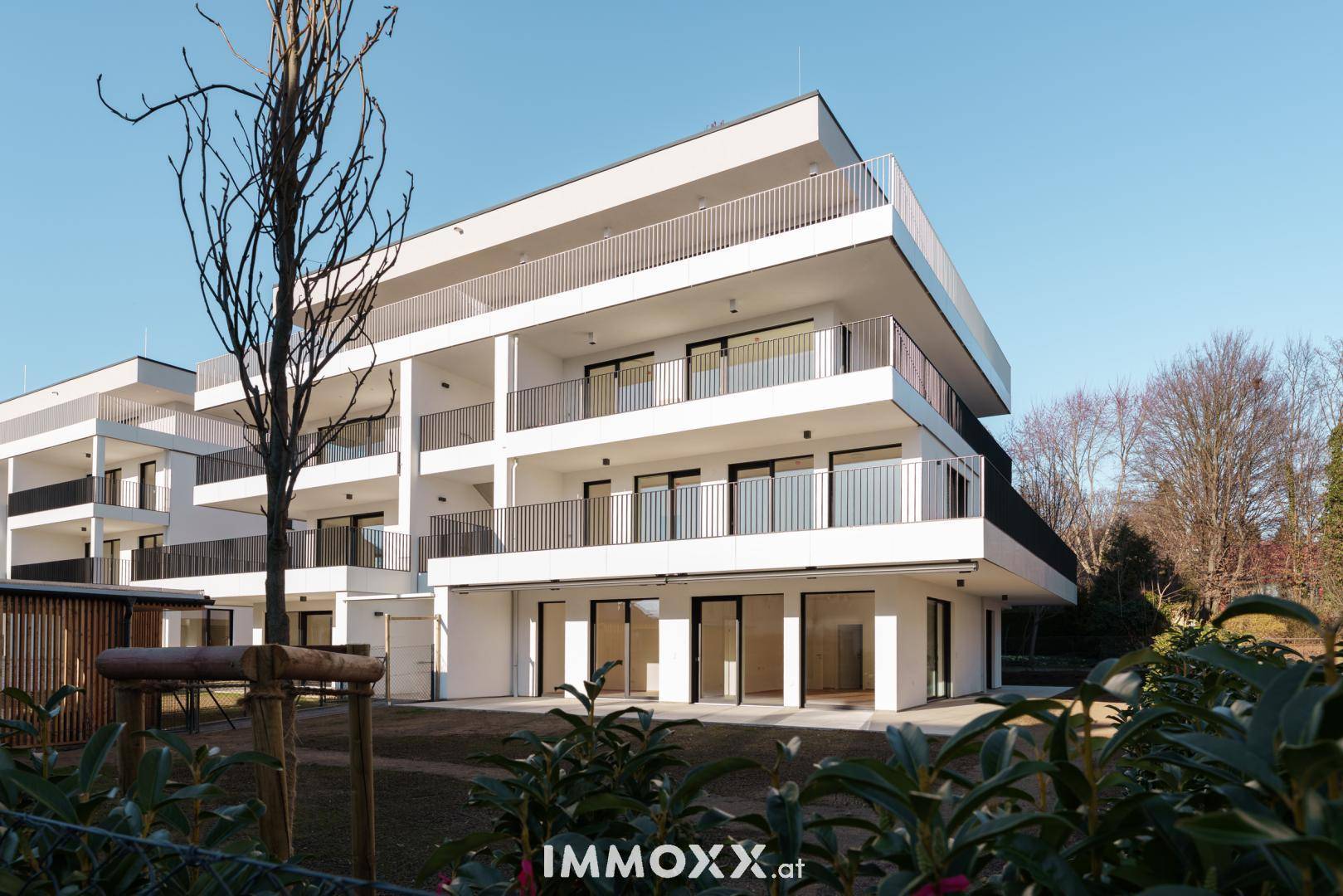 Neubau-Wohngebäude mit moderner Architektur, großzügigen Balkonen und umliegender Grünfläche.