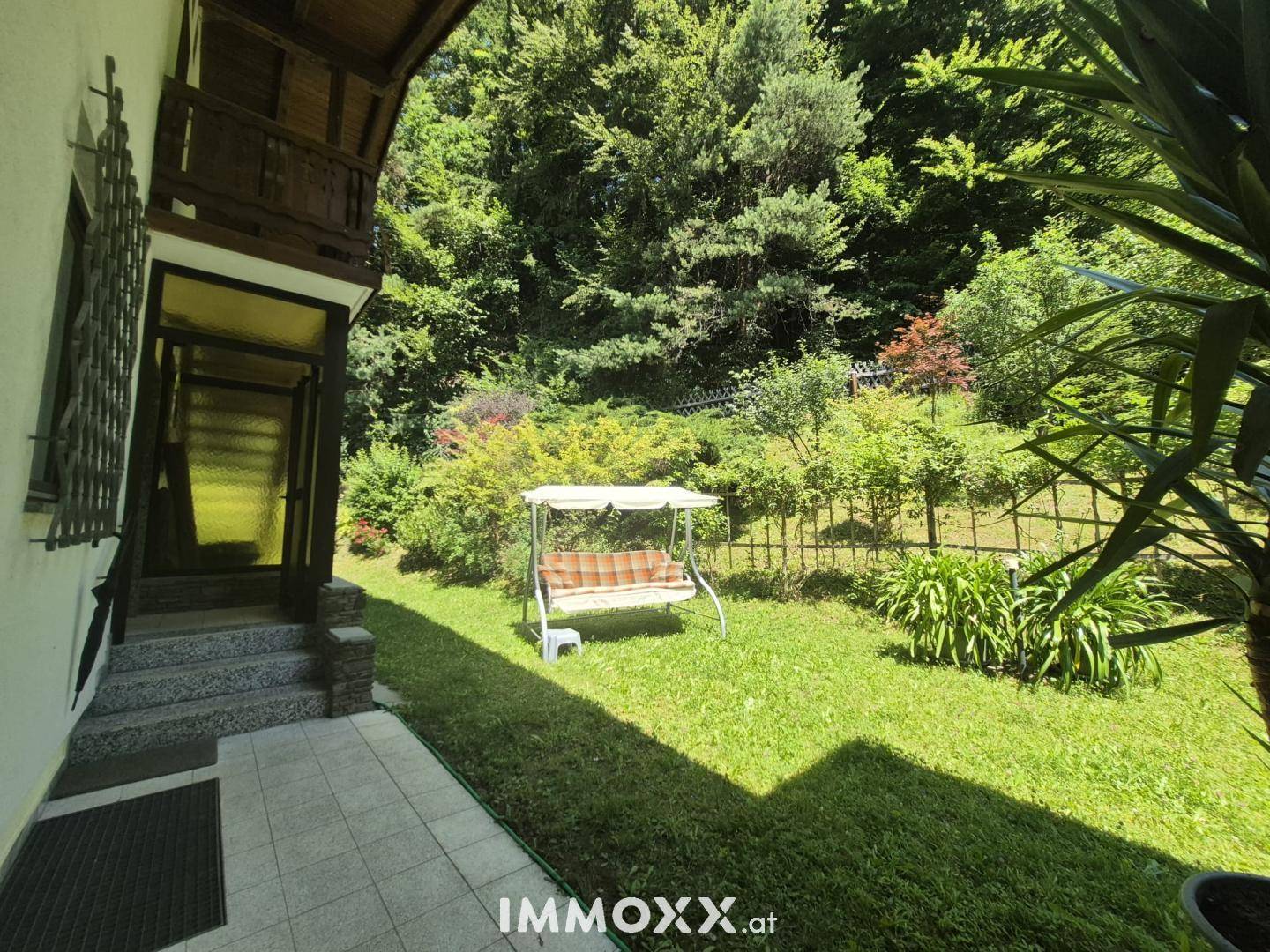 Sonniger Gartenbereich mit Rasen, Schaukel und direktem Zugang zur Terrasse des Hauses.