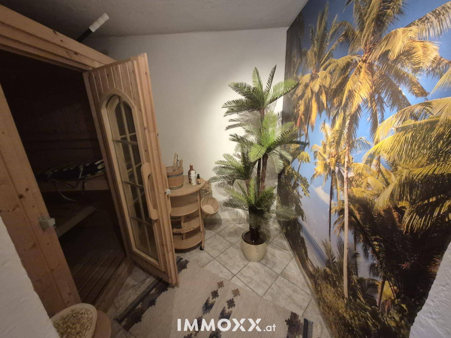 Entspannungsbereich mit einer Holzsauna und tropischer Wandgestaltung, ideal für Wellness.
