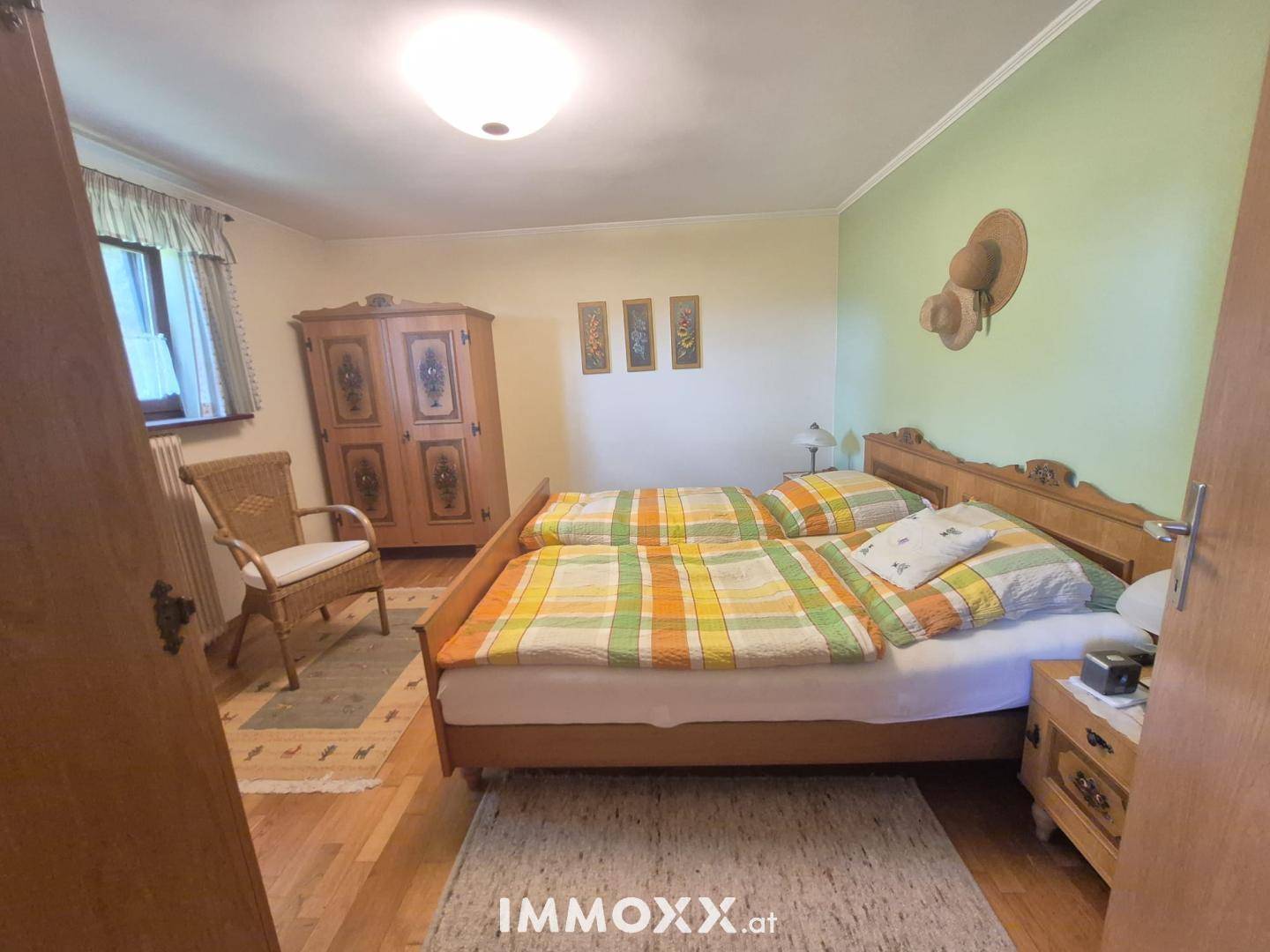 Gemütliches Schlafzimmer mit Doppelbett, Holzschrank und farbenfroher Bettwäsche.