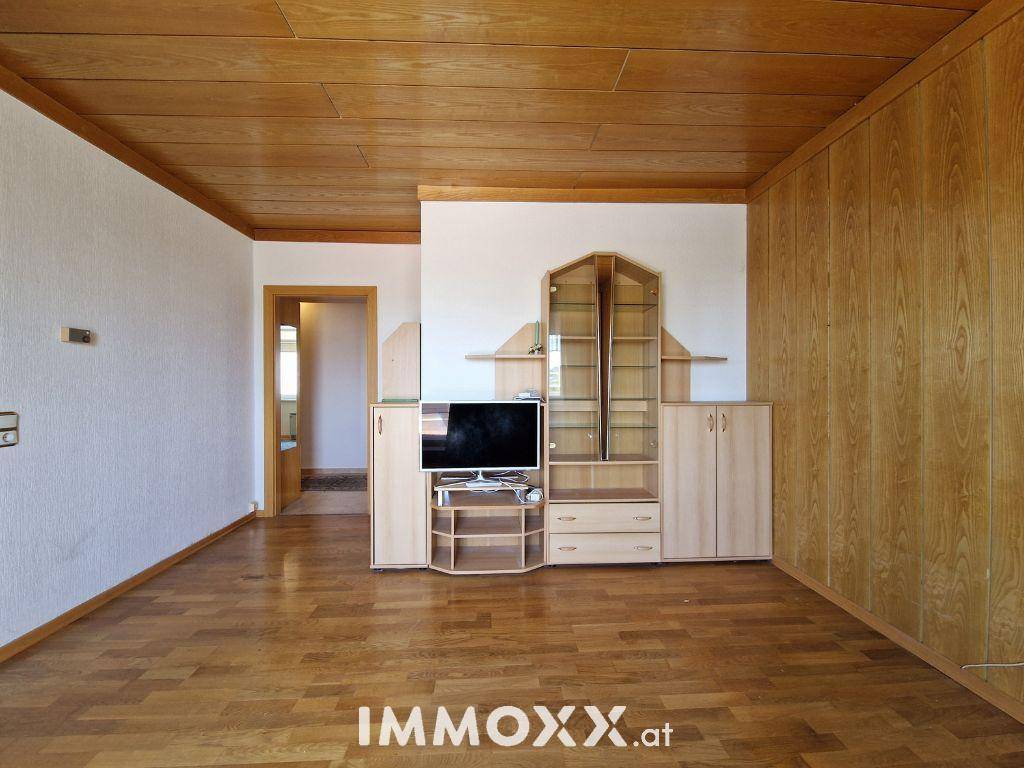 Geräumiges Wohnzimmer mit Holzdecke, Holzboden und einer Medieneinheit.