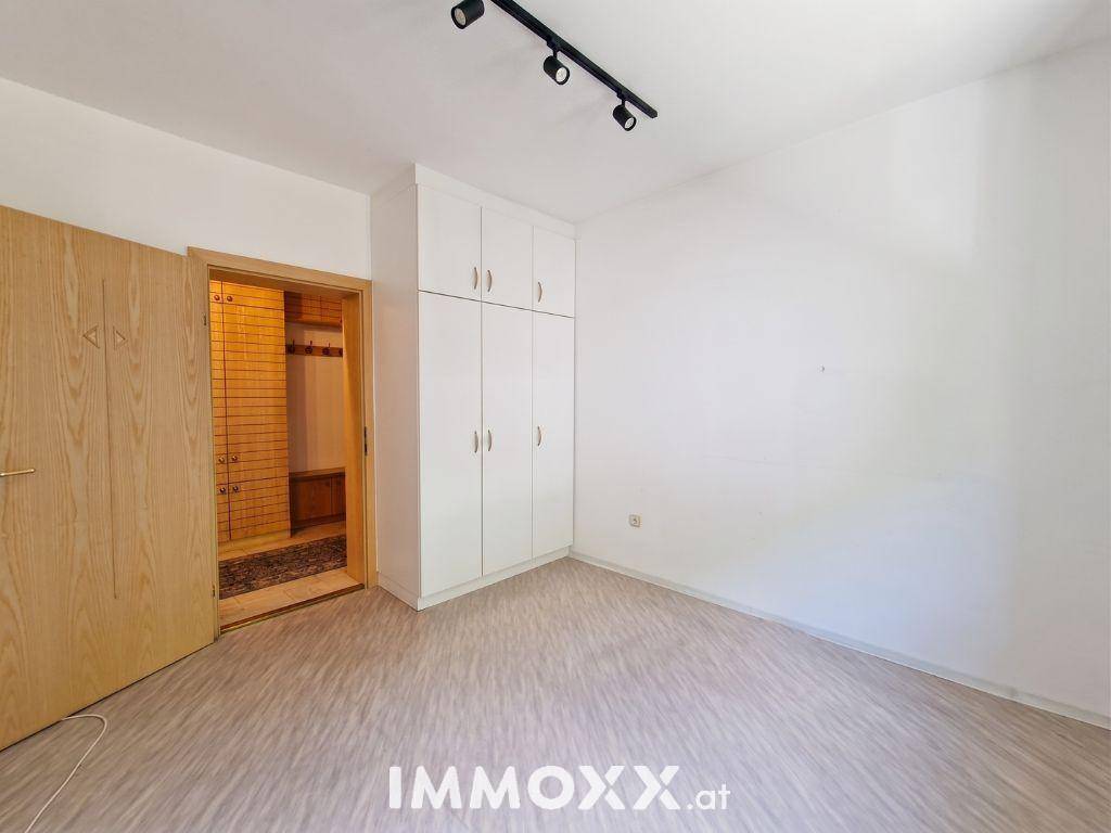 Helles, leeres Zimmer mit Laminatboden und einem praktischen Einbauschrank.