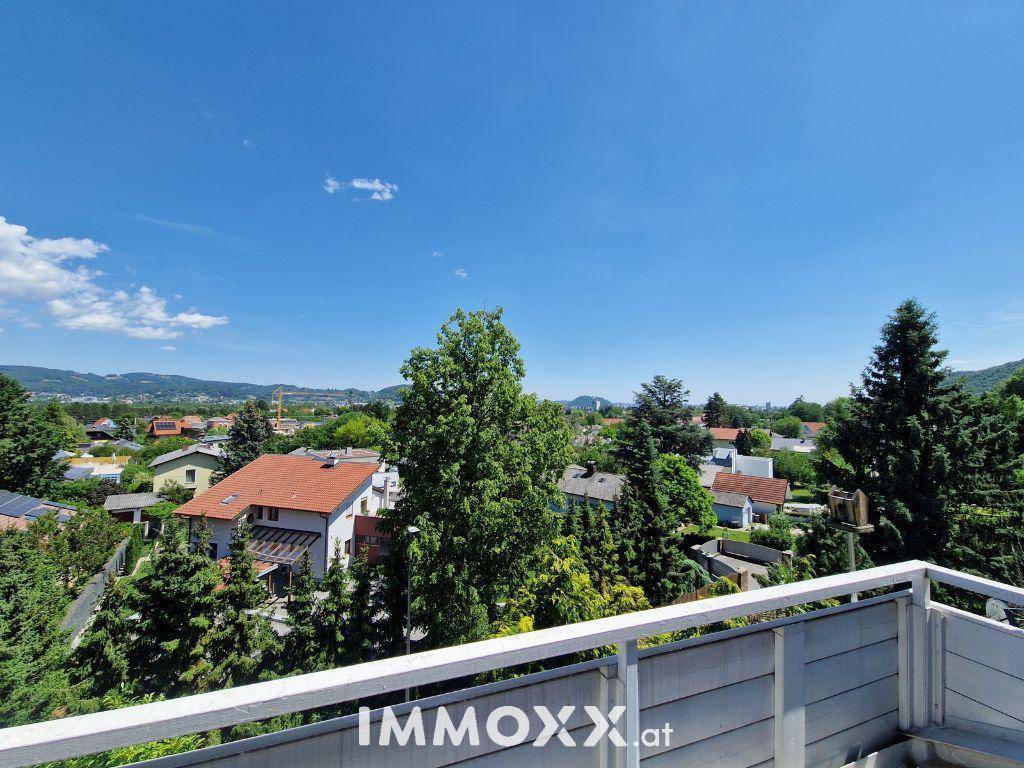Panoramablick vom Balkon über die grüne Landschaft und die umliegenden Berge.