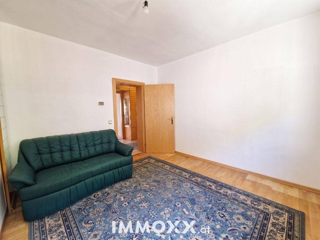 Gemütliches Wohnzimmer mit grünem Sofa, Holzboden und einem traditionellen Teppich.