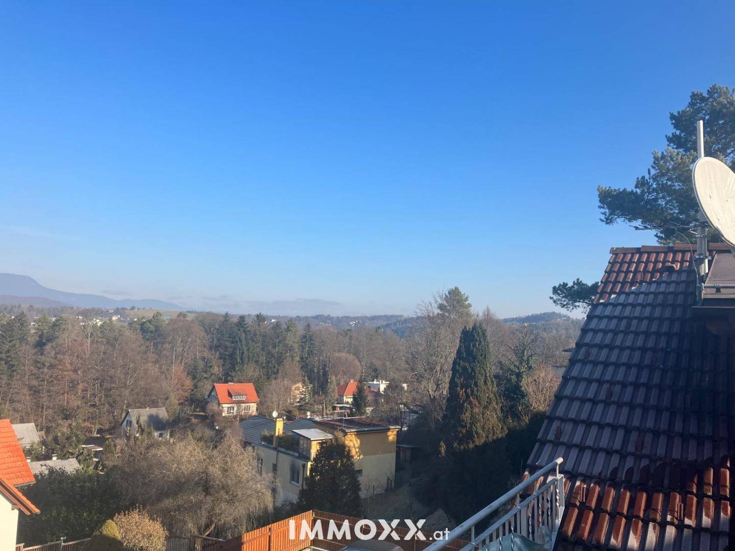 Aussicht über Dächer und Bäume einer Wohnsiedlung mit weitem Blick in die Landschaft.