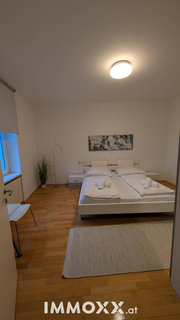 Geräumiges Schlafzimmer mit großem Doppelbett, Stehlampe und hellem Holzfußboden.