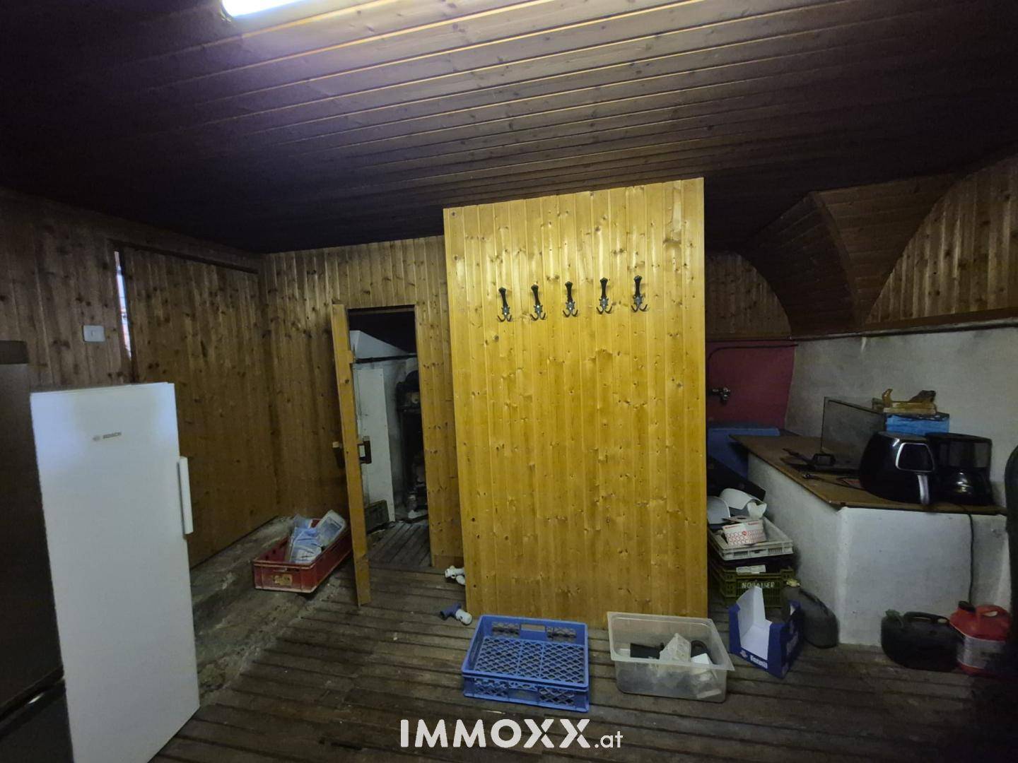 Rustikaler Abstellraum mit Holzverkleidung, Kühlschrank und Stauraum.