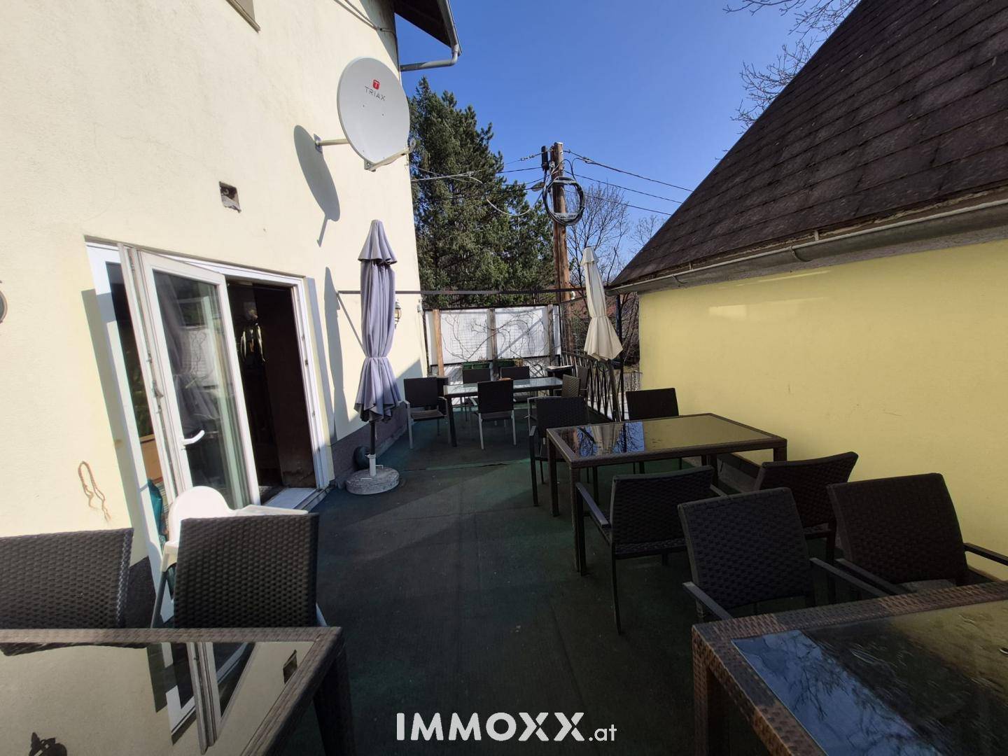 Große Terrasse mit vielen Tischen und Stühlen, ideal für gesellige Runden im Freien.