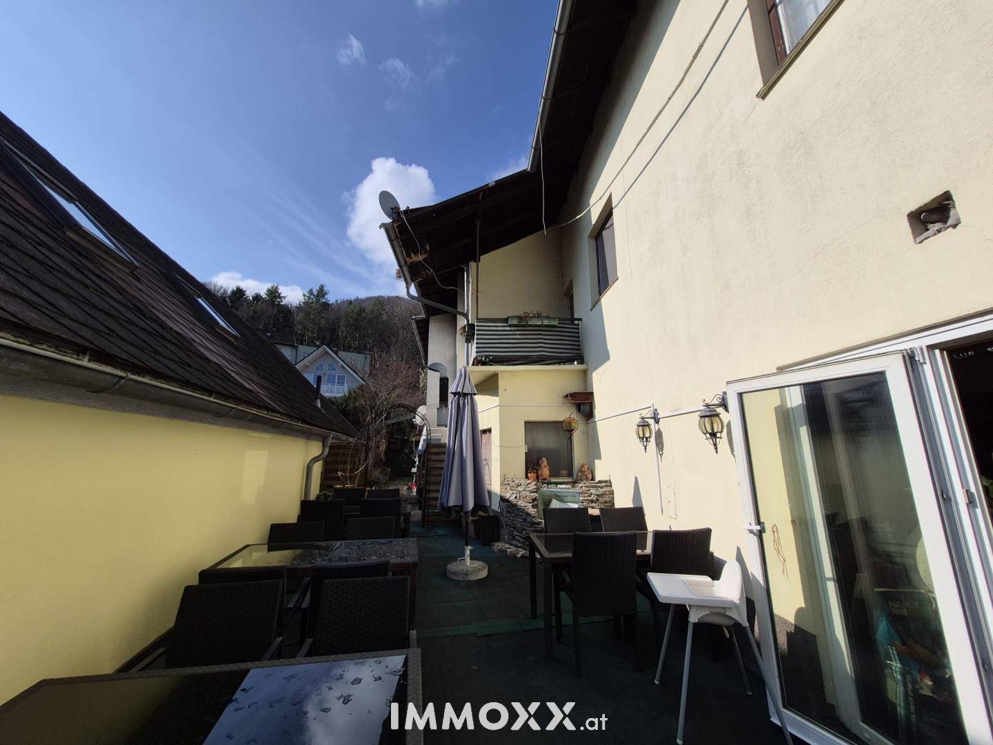 Weitläufige Terrasse mit Außenmöbeln und Blick auf die umliegende Hügellandschaft.