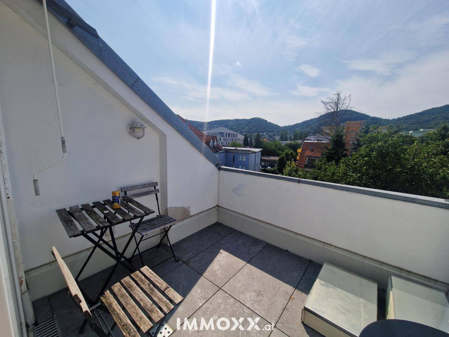 Gemütliche Dachterrasse mit Holztisch und Stühlen, ideal für entspannte Stunden im Freien.