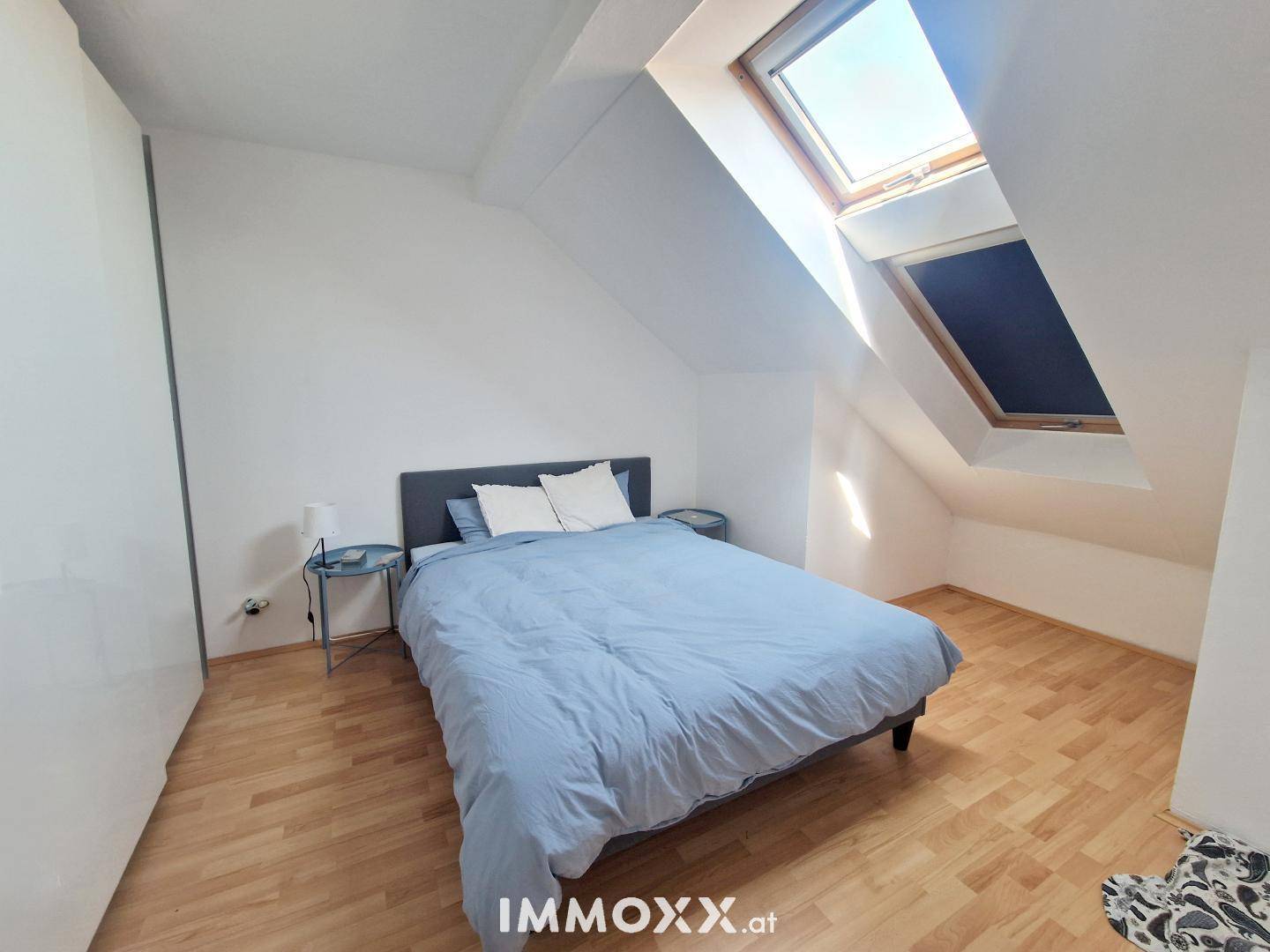 Gemütliches Schlafzimmer mit Doppelbett, Holzboden und einem großen Dachfenster für viel Licht.