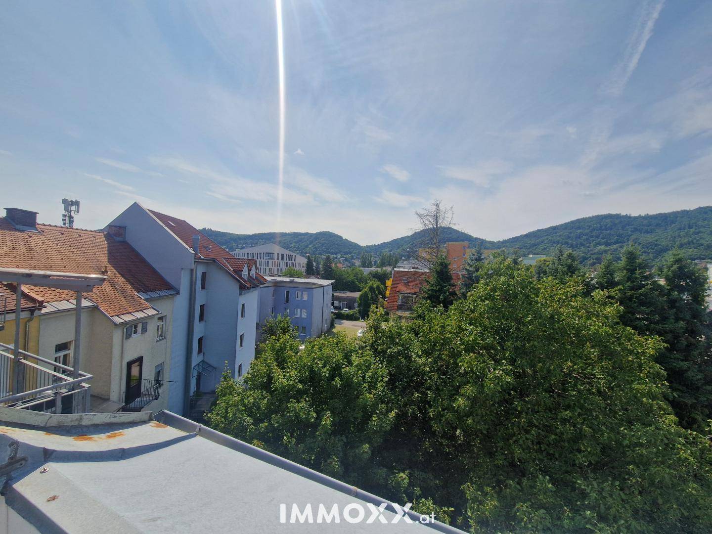 Panoramablick von der Dachterrasse auf die Stadt und die grünen Hügel in der Ferne.
