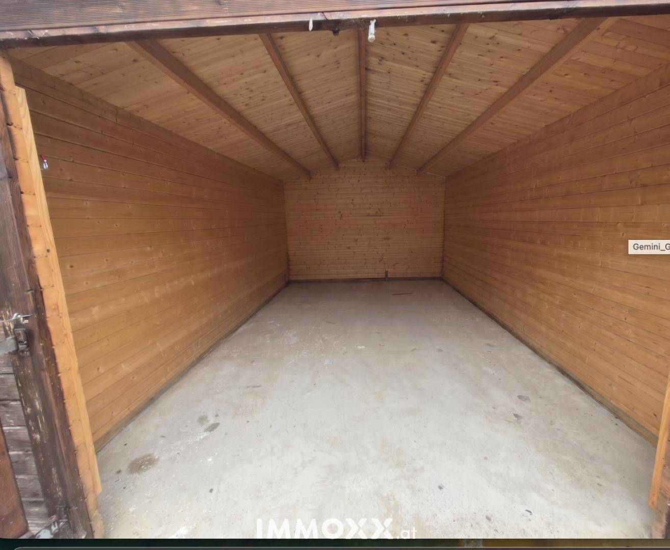 Leere Garage mit Holzverkleidung und Betonboden, bereit zur Nutzung.