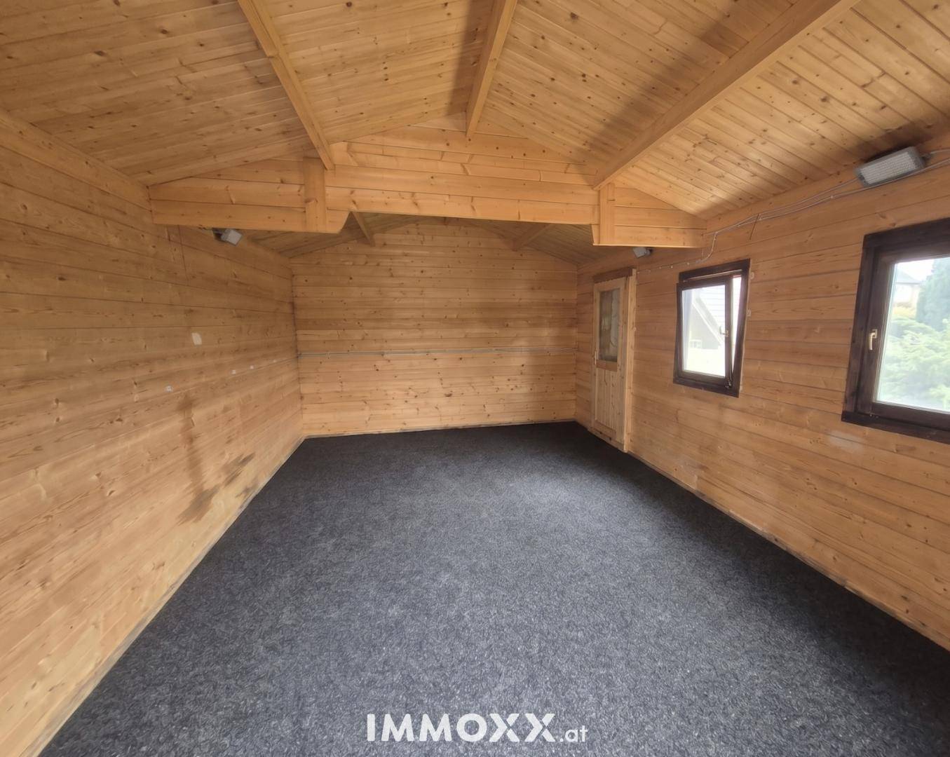 Geräumiger Innenraum eines Holzhauses mit Holzverkleidung und Teppichboden.