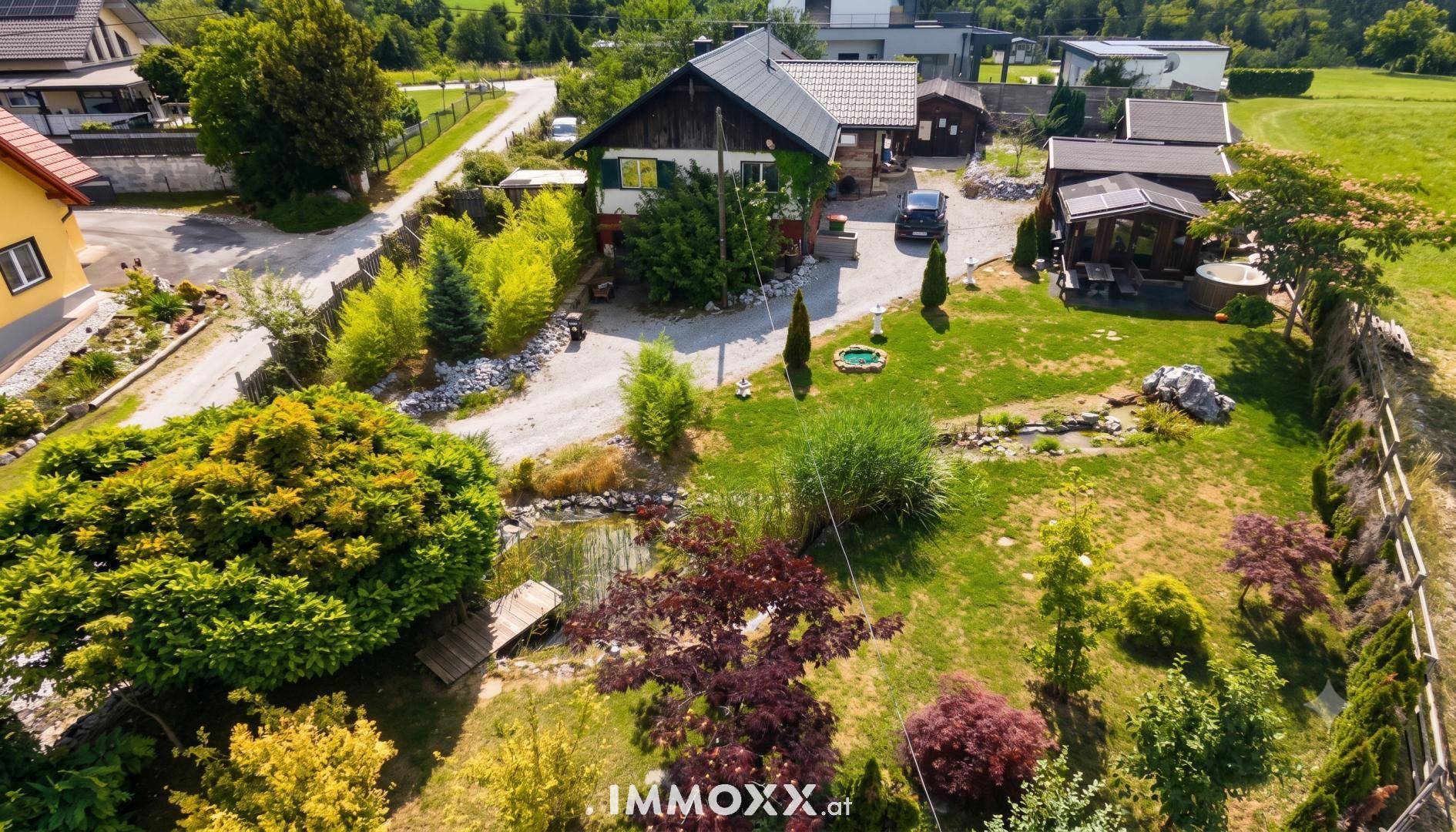 Luftaufnahme des Anwesens mit großem Garten, Teich, Zufahrt und umliegender Landschaft.